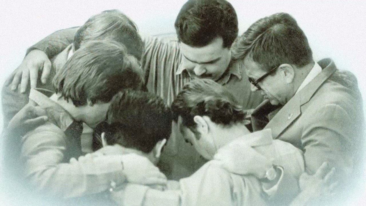 Chuck Colson huddled around with other men praying